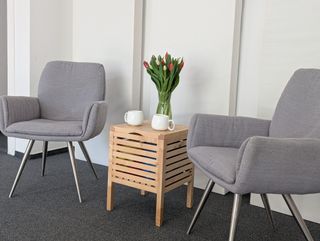 Zwei graue Sessel mit kleinem Holztisch, darauf Tulpen und zwei Tassen